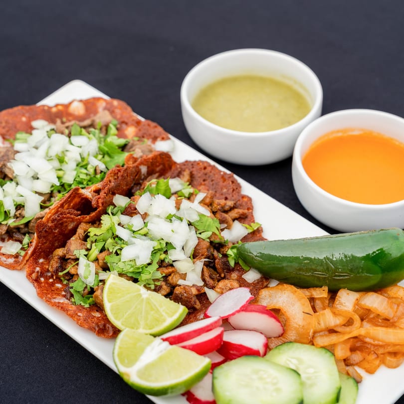 Blady's Tacos with meat, cilantro, onions, lime, radishes, cucumbers, and two sauces.