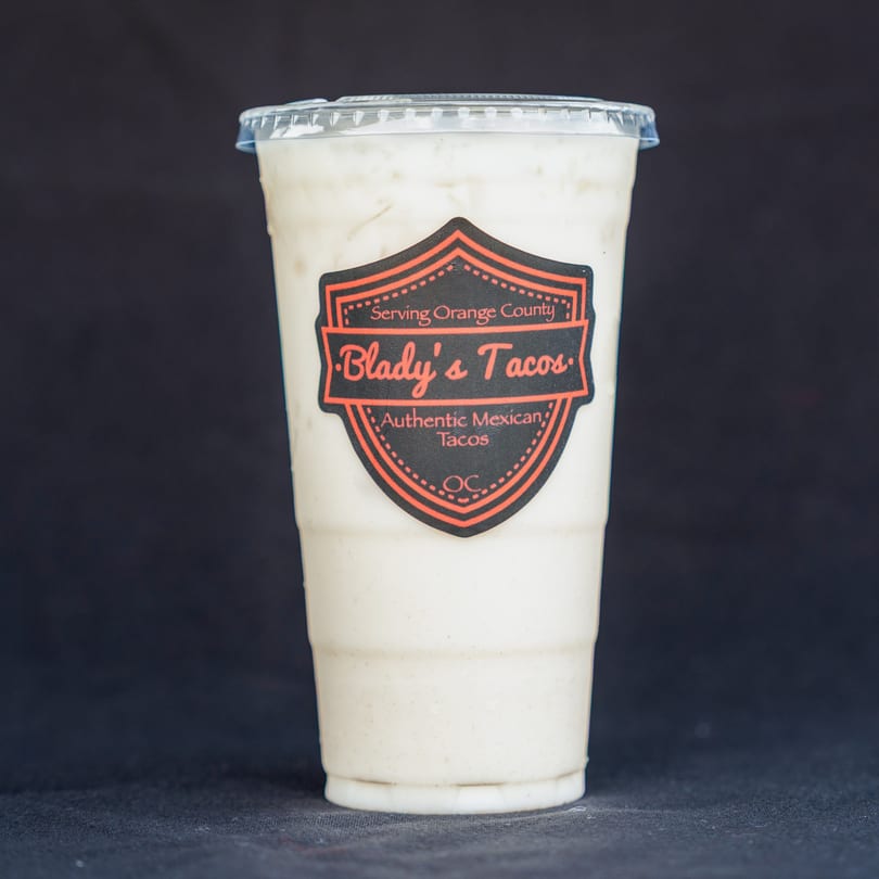A Blady's Tacos horchata drink in a clear plastic cup with a branded label.