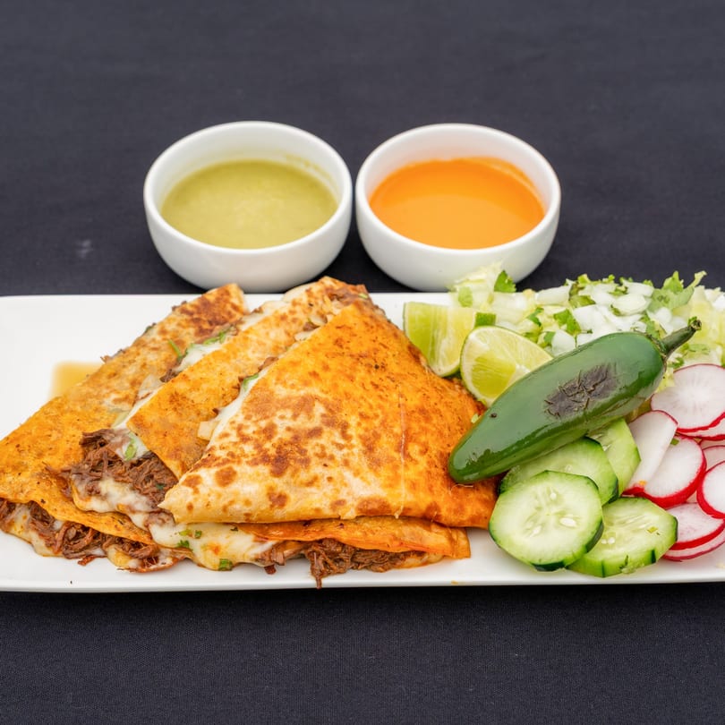 Blady's Tacos birria quesadillas with melted cheese, two sauces, and a side salad with jalapeño.